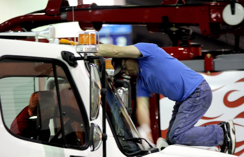 Hi-Vac employees Dean Peake, left, and Kent Parks, right clean the windshield of a hydroexcavator in the company's booth at the WWETT Show during set-up on Tuesday.