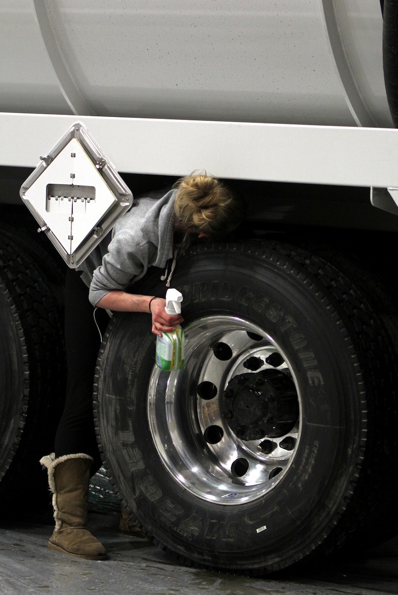 Meghan Heid squeezes between the truck and its wheel as she cleans it in Presvac booth on Tuesday during WWETT Show setup.